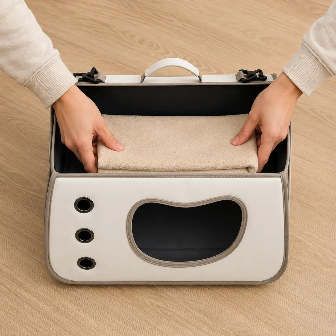 Deux mains posent une serviette beige pliée au fond du sac bandoulière ouvert, aux dimensions exactes de la base